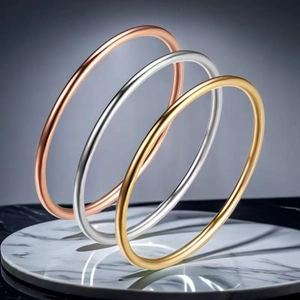 Three minimalist polished stainless steel bangle bracelets in gold, silver, and rose gold