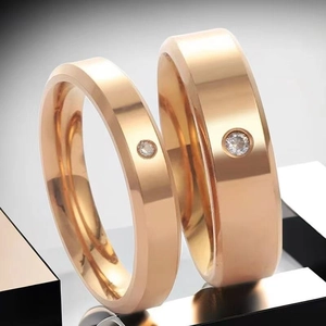 Close-up of rose gold titanium steel couple rings with flat band and inset crystal stones