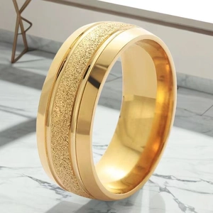 Dettaglio di un anello largo dorato con finitura opaca satinata e bordi lucidi