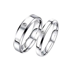 Polished stainless steel couple ring set featuring single inlaid zircons on white background