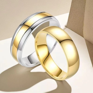 Detailed close-up of two-tone and gold polished stainless steel couple rings on a beige stand