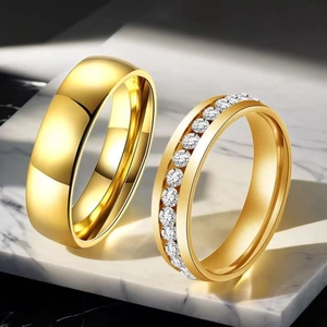 Close-up of gold stainless steel couple rings with a polished band and a zircon pave band