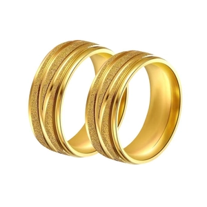 Pair of matte gold titanium steel rings with polished edges on a white background