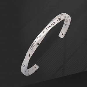 Detail of engraved always in my heart text and geometric symbols on a steel cuff bracelet