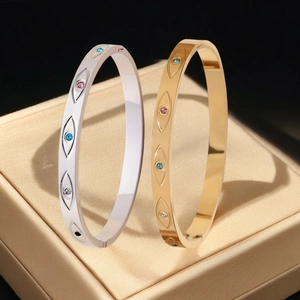 Detalle de brazaletes de ojo turco oro y plata con circonitas sobre una caja de regalo