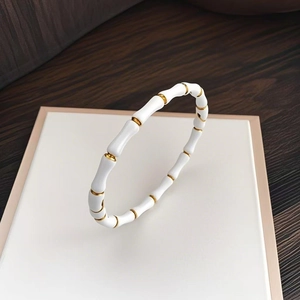 Gros plan d'un bracelet en émail blanc en forme de bambou avec des accents dorés