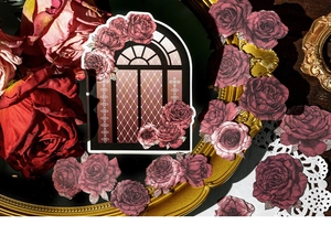Macro shot of vintage rose themed stickers featuring an ornate window and red petals