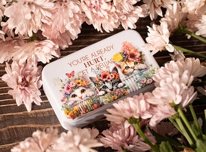 Charming tin storage box with cat illustrations and floral accents on wood background