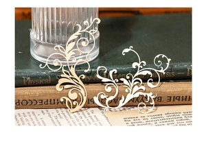 Macro detail of laser-cut Baroque scroll paper inserts for scrapbooking and DIY crafts