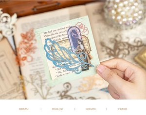 Detailed view of hollow vintage scrapbooking cards featuring lace feathers and floral patterns