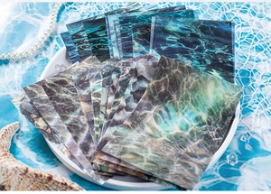 Detail van scrapbookpapier met blauwe waterrimpels en decoratieve parels en schelpen