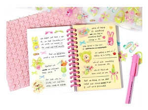 Close-up of spiral notebook with cute cartoon illustrations and pink heart bubble wrap
