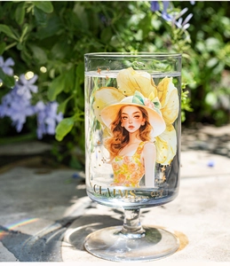 Detail of clear glass with vintage girl illustration in outdoor garden setting