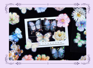 Macro detail of holographic butterfly and floral stickers with shimmering laser effect on black