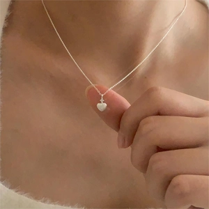 Close-up of minimalist 925 sterling silver heart pendant necklace on a neck model