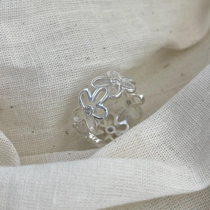 Macro detail of S925 sterling silver flower ring with zircons on linen background