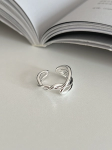 Macro detail of silver adjustable criss cross ring on a textured white surface