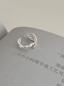 Detailed view of S925 silver irregular layered cross ring on minimalist magazine background