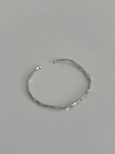 Macro detail of silver S925 minimalist irregular wave cuff bracelet with polished finish