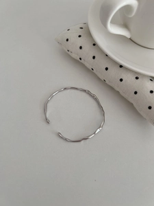 Close-up of S925 silver irregular wave bangle with polished finish on white background