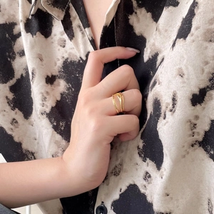 Minimalist S925 silver layered intertwining gold ring worn against a cow print shirt