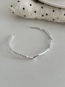 Macro detail of irregular wavy hammered texture on a polished silver open bangle