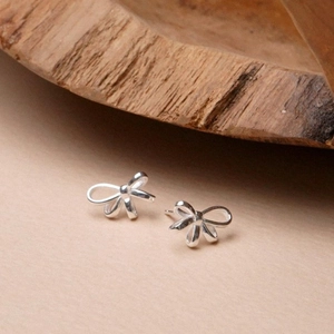 Minimalist S925 silver bow stud earrings displayed on a rustic wooden background