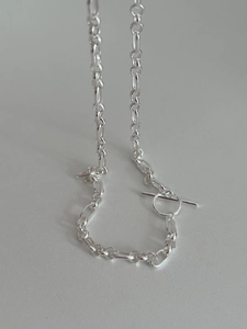 Macro shot of S925 silver link chain with elegant T-bar toggle clasp on a textured surface