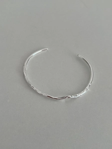 Detailed macro view of the irregular hammered liquid metal texture on the silver bangle