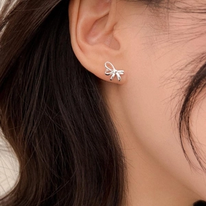 Detail view of dainty S925 silver bow stud earrings worn by model for daily wear