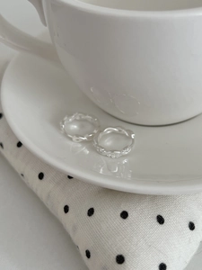 Détail de créoles torsadées en argent avec zircons incrustés sur soucoupe en céramique