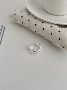 Détail d'une bague multicouche en argent S925 sur un bureau au style épuré