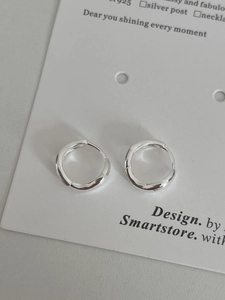 Vue macro de boucles d'oreilles créoles minimalistes en argent sterling S925 sur carte