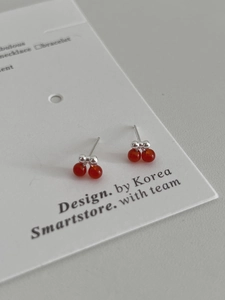 Macro shot of S925 silver cherry earrings with red beads on a white display card