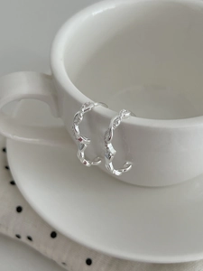 Détail macro de créoles torsadées en argent avec zircon sur une tasse en céramique