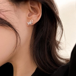 Close-up of S925 sterling silver bow stud earring worn by a model in soft light