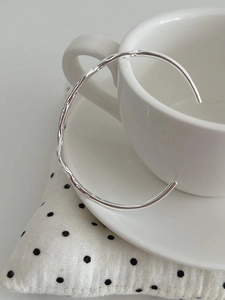 Detail of S925 sterling silver hammered cuff bracelet hanging on a white coffee cup