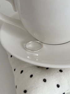 Macro detail of S925 sterling silver stamp on minimalist wave ring on porcelain cup