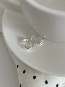 Détail macro des créoles en argent sterling S925 sur un plat en céramique décoratif
