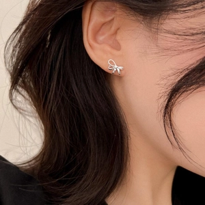 Macro side view of elegant S925 silver bow stud earring worn on a model's ear