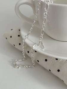Detailed view of silver S925 chain with industrial OT toggle clasp on white ceramic