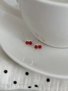 Detailed macro view of S925 silver cherry earrings with red beads and bow accents