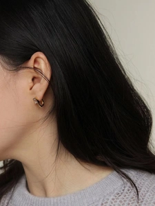 Détail de créoles en argent 925 doré avec un zircon rectangulaire porté à l'oreille