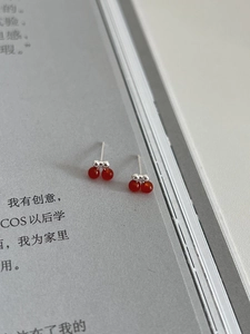 Macro detail of red cherry stud earrings in S925 sterling silver on magazine