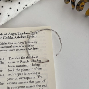 Minimalist S925 sterling silver open bangle with irregular wavy texture on book page