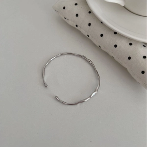 Minimalist S925 silver open bangle with irregular wavy texture on grey surface
