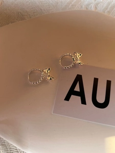 Détail de boucles d'oreilles nœud en argent 925 avec anneau perlé sur un plateau en céramique