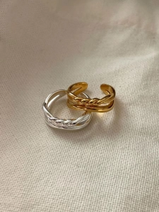 Close-up of 925 silver and 18K gold braided knot rings on minimalist linen fabric