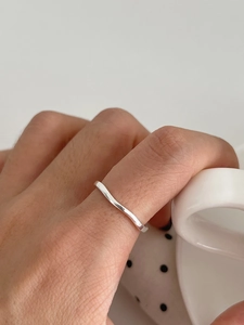 Detail of minimalist wavy silver ring on hand holding a white ceramic handle