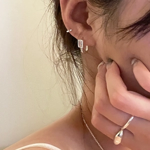 Détail de boucles d'oreilles et bijoux en argent 925 sur modèle au style minimaliste